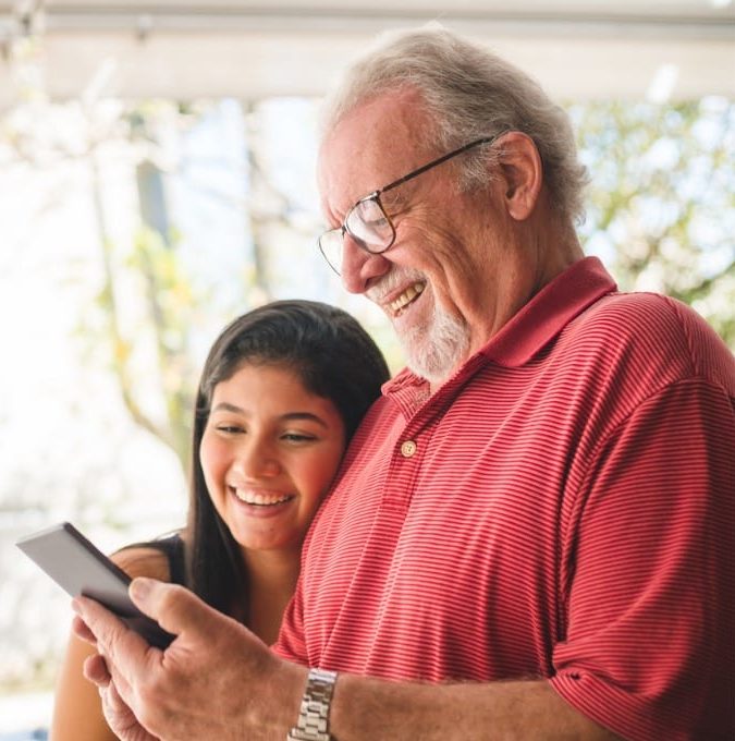 grandpa shows photos on his cell phone for his granddaughter picture id1141804282 e1573758920167