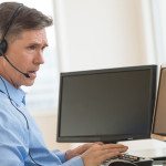 Trader Using Multiple Computer Screens While Communicating Throu